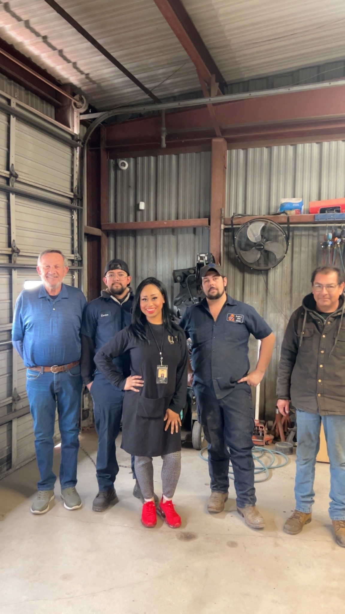 Chef Amelia standing with four people inside a local auto shop