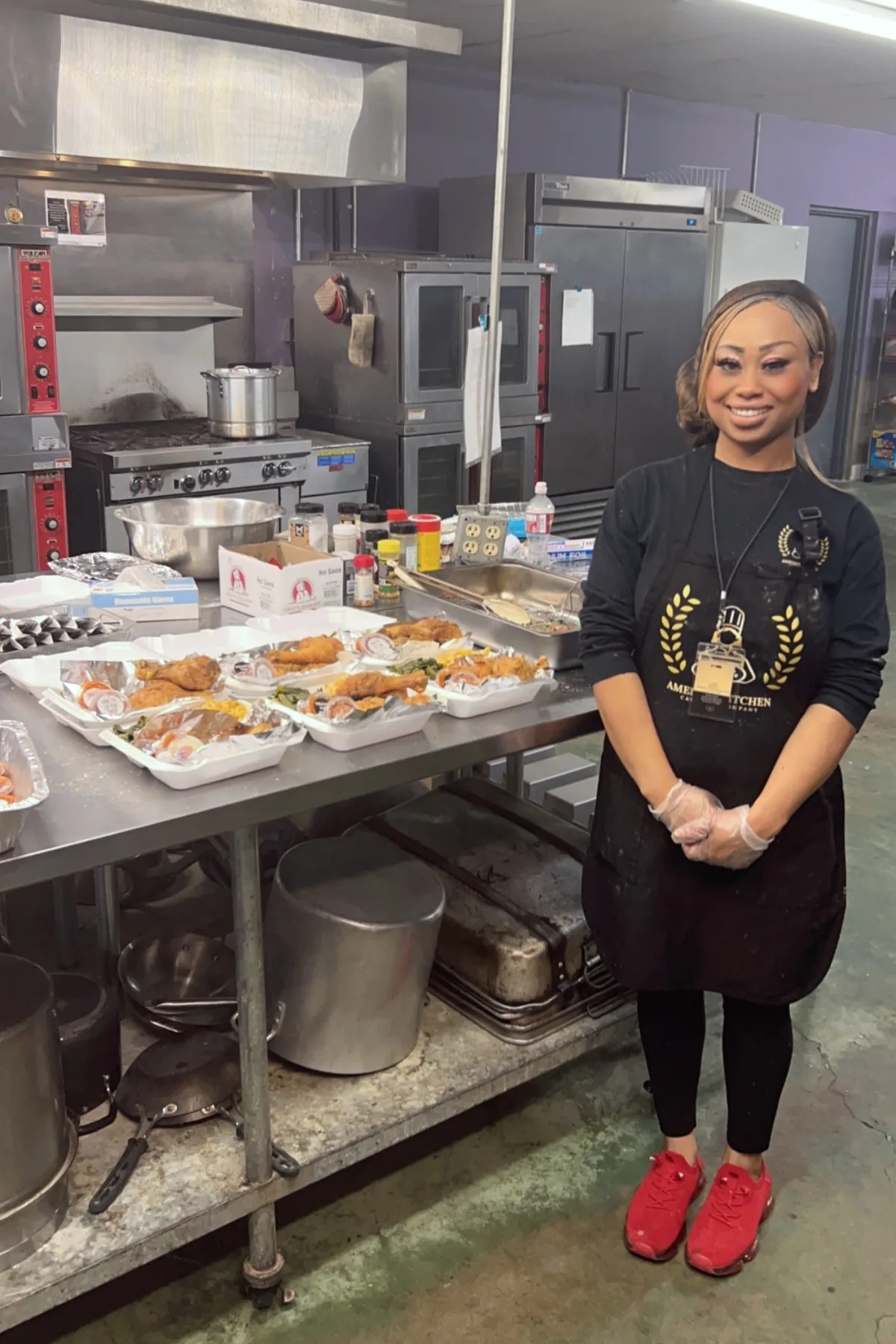 Chef Amelia beside a prep table of plated meals in her commercial kitchen