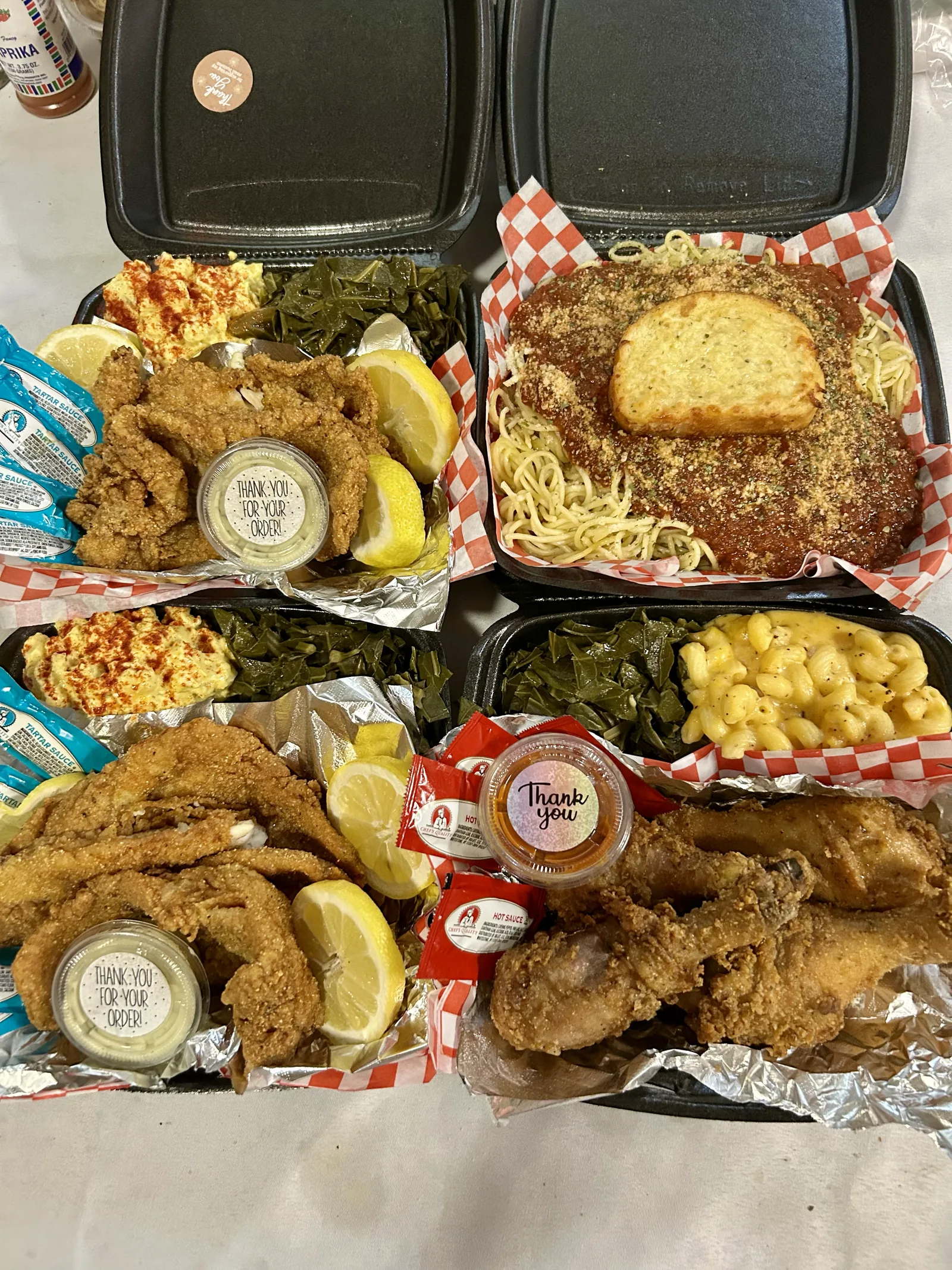 Several individually packaged plates of catfish, spaghetti, greens, and mac and cheese